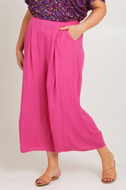 Model Poppy wearing size 16 of the Olympia Pant in colour Frenchrose (Pink), from the front, cropped image