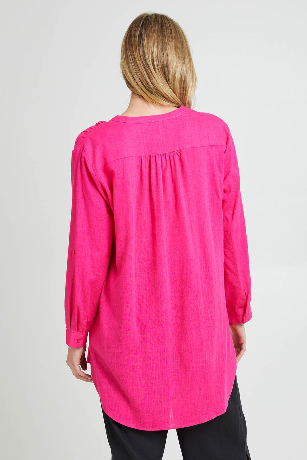 Model Grace wearing size 10 of the Beach Tunic Shirt in colour Berry (Pink), from the back