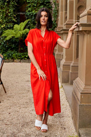 A model wearing the Simone Dress in colour Cherry (Red), from the front, showing the whole outfit