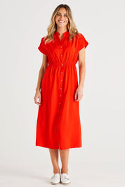 A model wearing the Simone Dress in colour Cherry (Red), from the front, showing the whole outfit