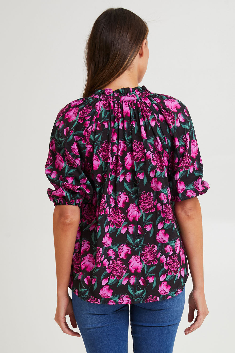 Model Madeline wearing size 10 of the Cecilia Blouse in colour Floral (Pink), from the back