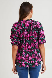 Model Madeline wearing size 10 of the Cecilia Blouse in colour Floral (Pink), from the back