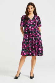 A model wearing the Florence Tiered Dress in colour Floral (Pink), from the front, showing the whole outfit