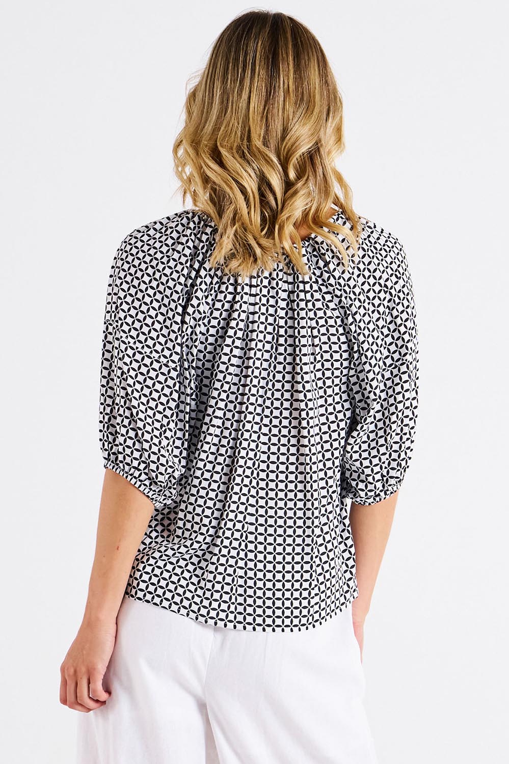 A model wearing the Camilla Blouse in colour Geometric (Black), from the back