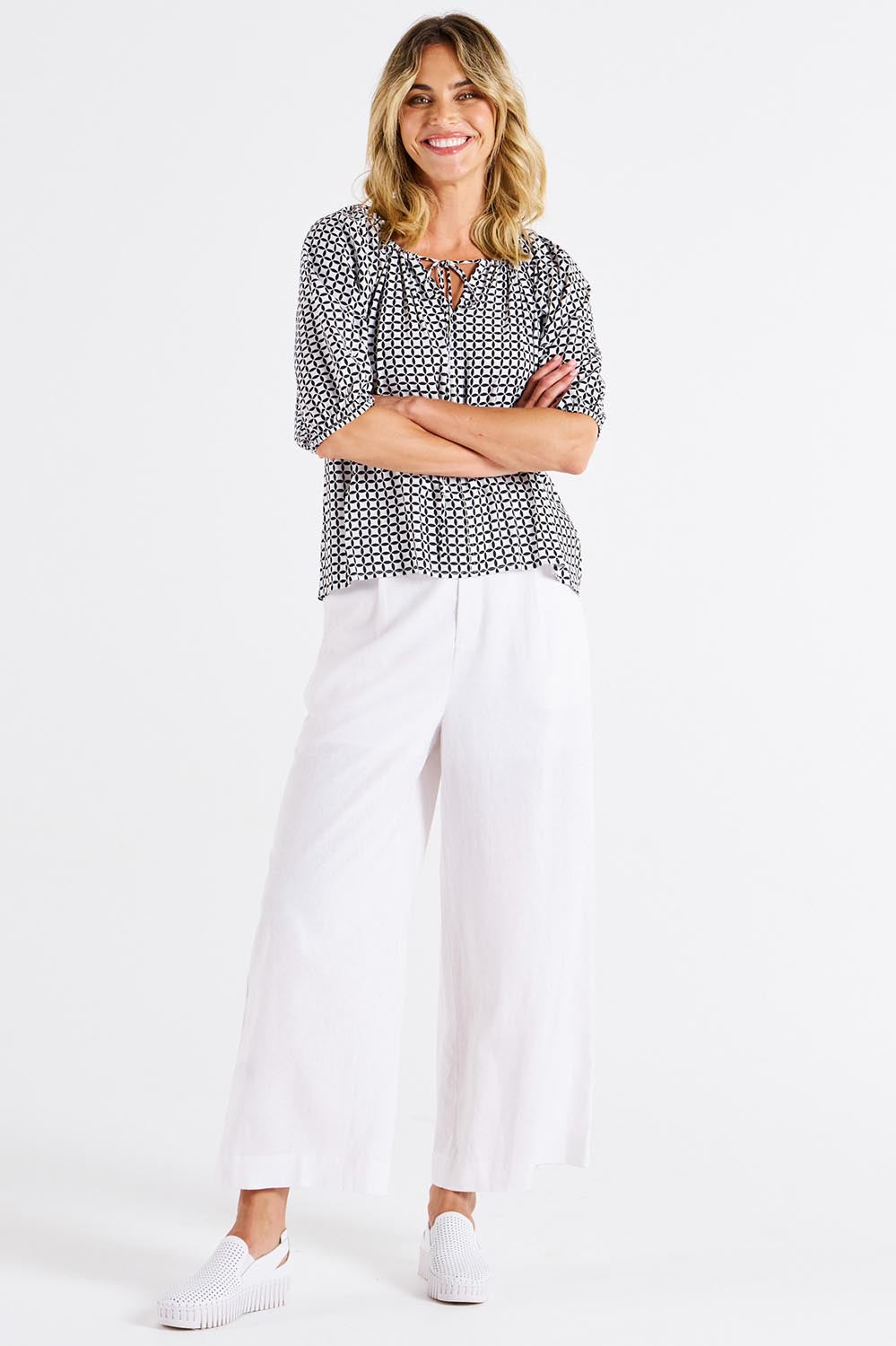 A model wearing the Camilla Blouse in colour Geometric (Black), from the front, showing the whole outfit