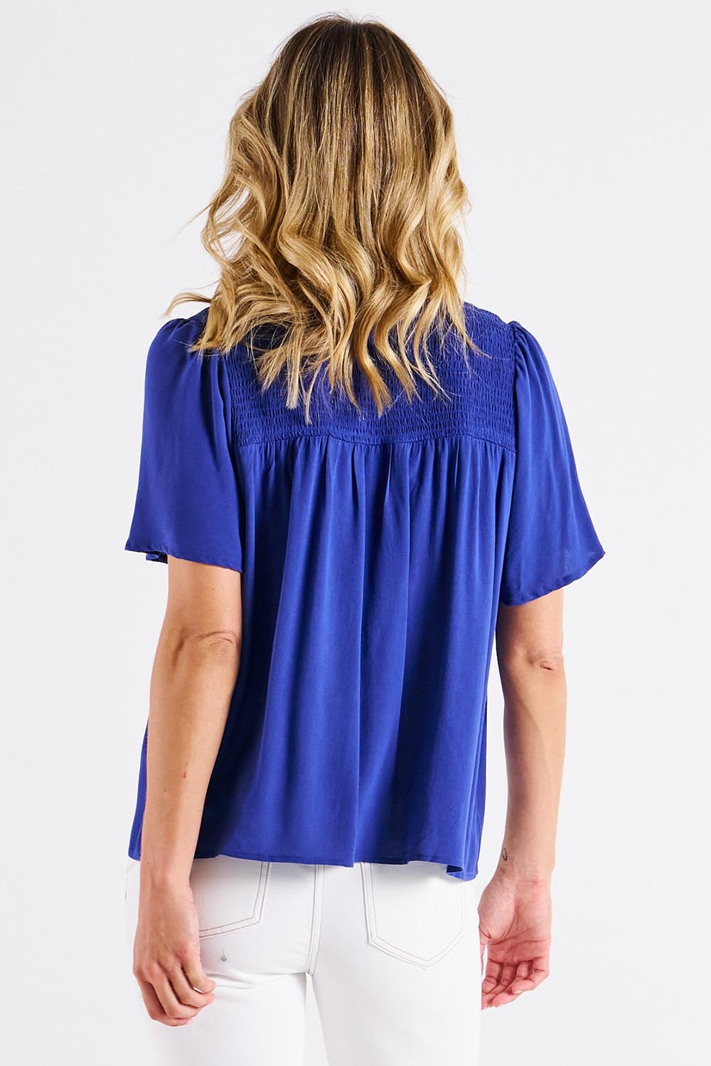 A model wearing the Sandy Shirred Blouse in colour Blue (Blue), from the back