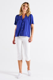 A model wearing the Sandy Shirred Blouse in colour Blue (Blue), from the front, showing the whole outfit