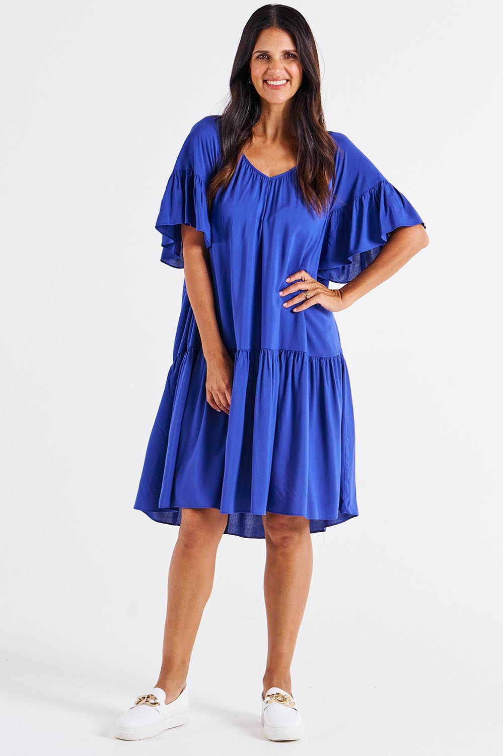 A model wearing the Bella Dress in colour Blue (Blue), from the front, showing the whole outfit