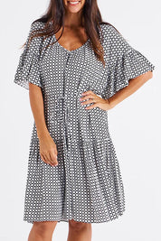 A model wearing the Bella Dress in colour Geometric (Black), from the front, cropped image
