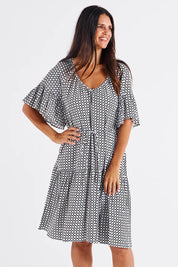 A model wearing the Bella Dress in colour Geometric (Black), from the front, cropped image