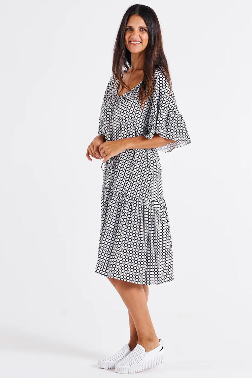 A model wearing the Bella Dress in colour Geometric (Black), from the front, showing the whole outfit