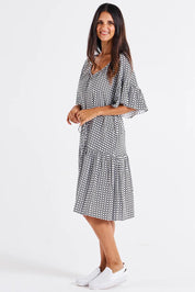 A model wearing the Bella Dress in colour Geometric (Black), from the front, showing the whole outfit