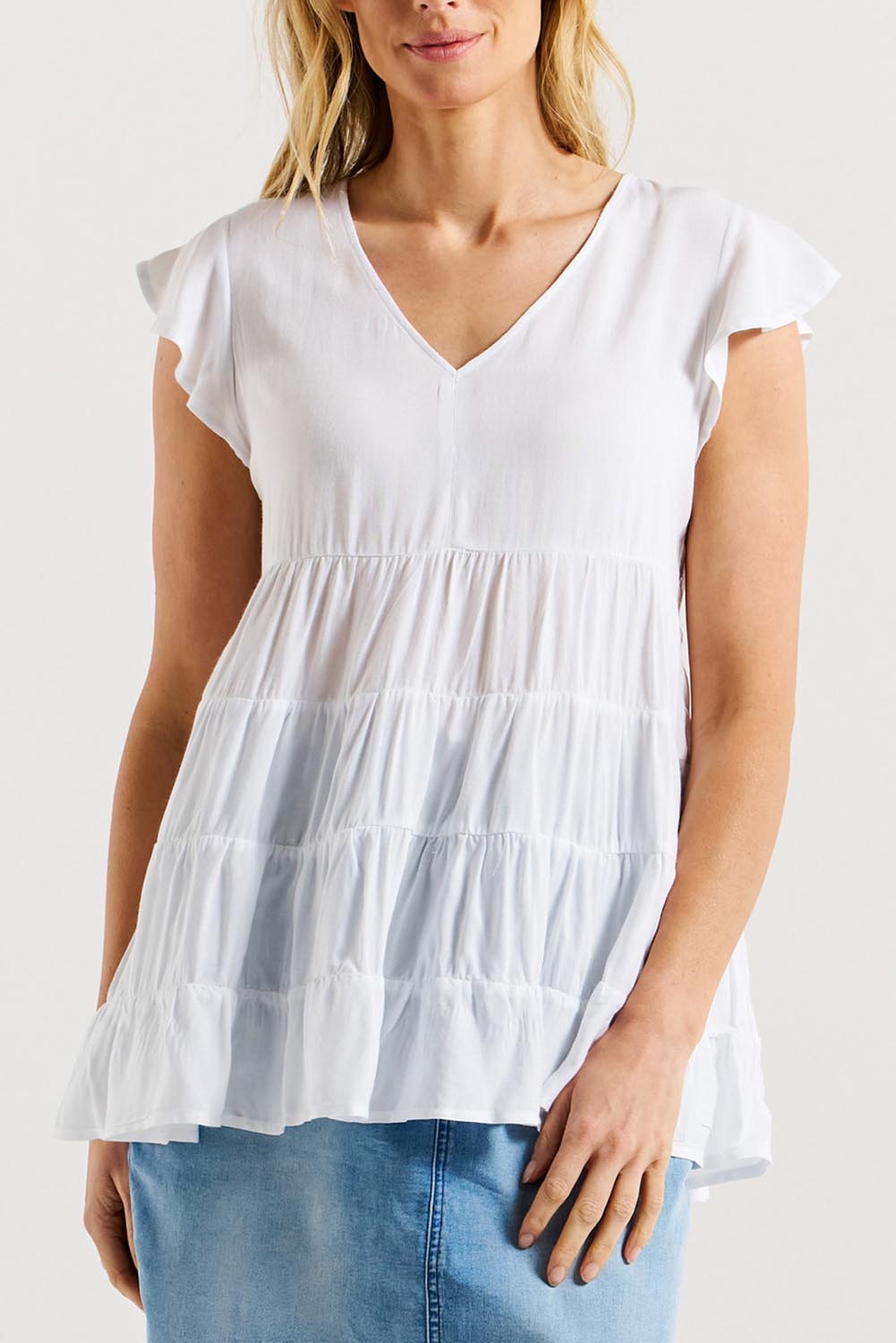 A model wearing the Danica Frill Top in colour White (White), from the front, cropped image