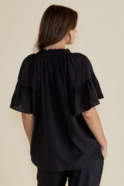 A model wearing the Vivienne Blouse in colour Black (Black), from the back