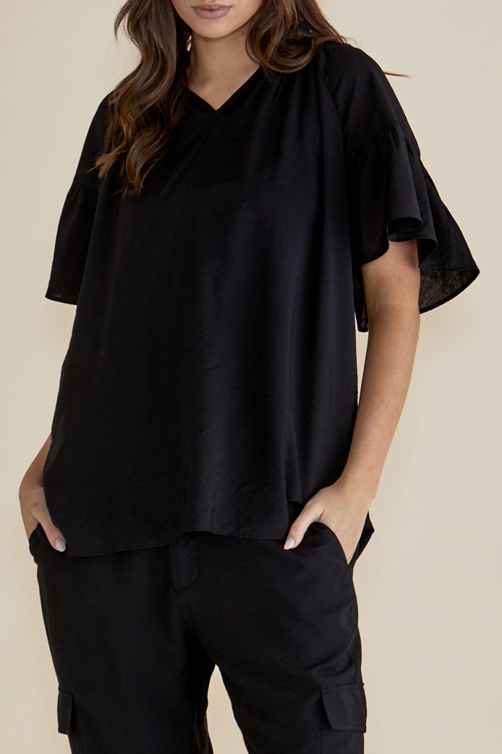 A model wearing the Vivienne Blouse in colour Black (Black), from the front, cropped image