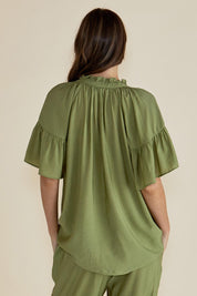 A model wearing the Vivienne Blouse in colour Pistachio (Green), from the back