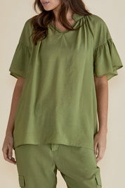 A model wearing the Vivienne Blouse in colour Pistachio (Green), from the front, cropped image
