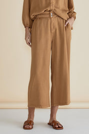 A model wearing the Rio Lyocell Relaxed Pant in colour Tan, from the front, cropped image