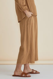 A model wearing the Rio Lyocell Relaxed Pant in colour Tan, from the front, cropped image