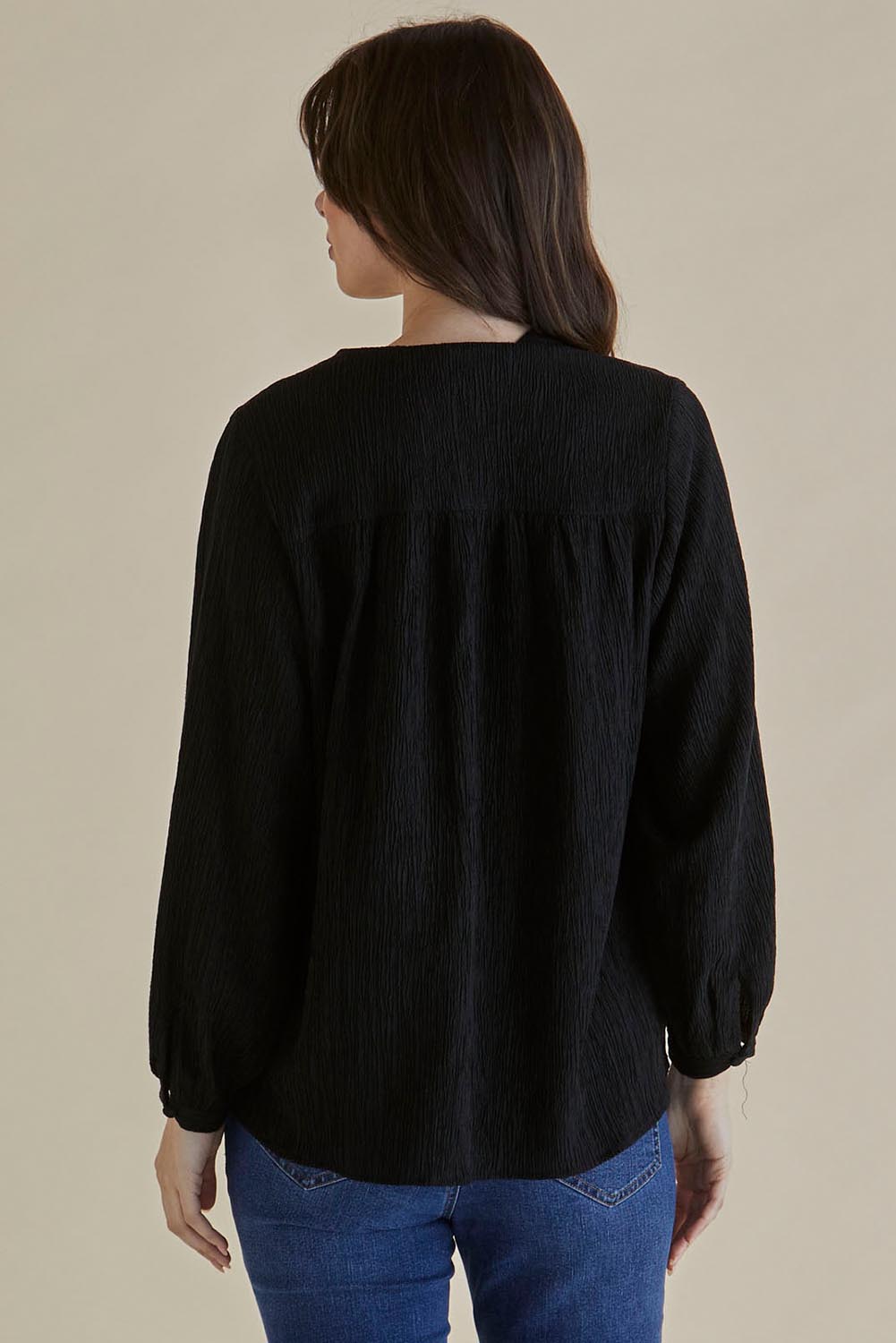A model wearing the Marie Blouse in colour Black (Black), from the back