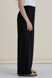 A model wearing the Zander Pant in colour Black (Black), from the front, cropped image