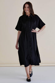 A model wearing the Dusk Dress in colour Black (Black), from the front, showing the whole outfit