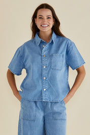 A model wearing the Saffra Short Sleeve Denim Shirt in colour Medwash (Blue), from the front, cropped image