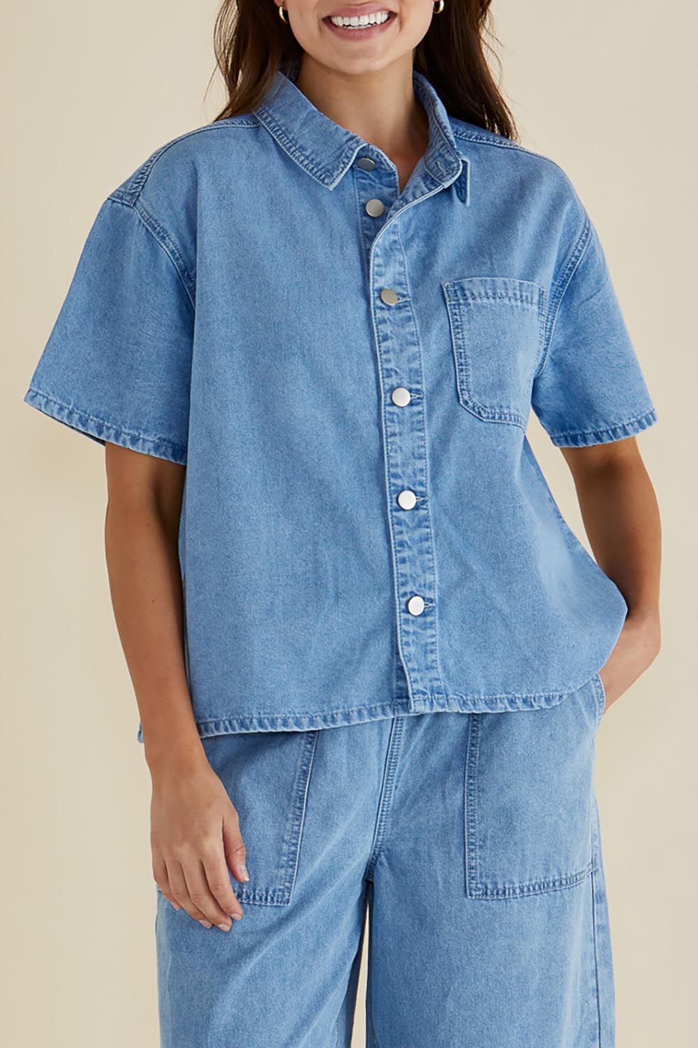 A model wearing the Saffra Short Sleeve Denim Shirt in colour Medwash (Blue), from the front, cropped image