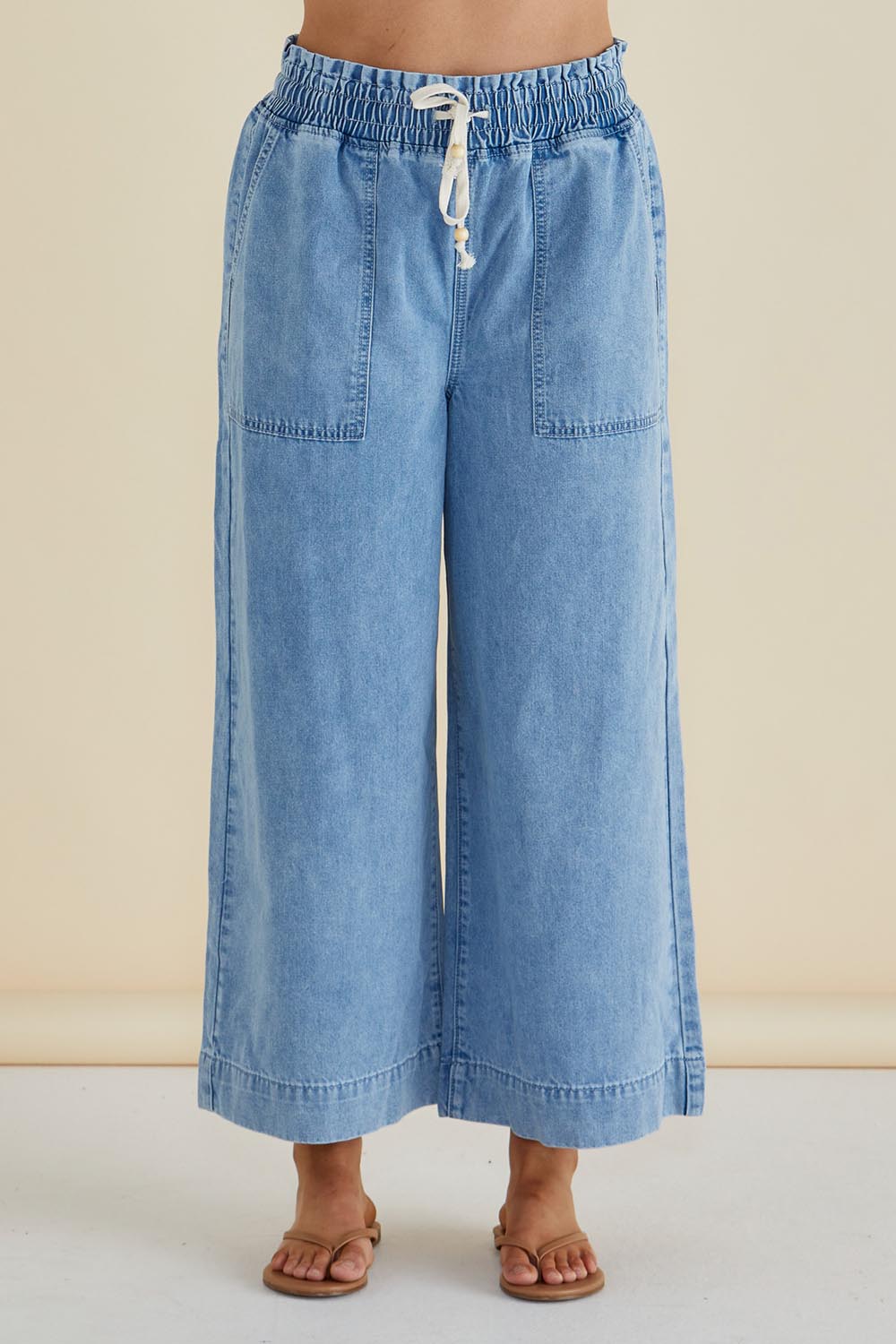 A model wearing the Saffra Relax Leg Jean in colour Midwash (Blue), from the front, cropped image