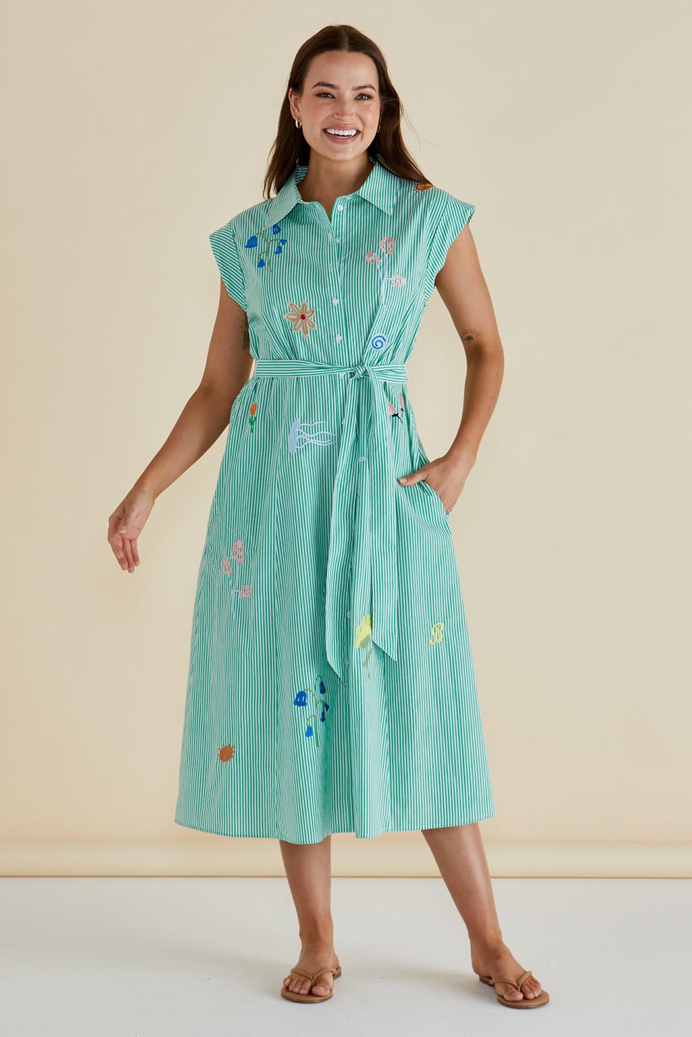 A model wearing the Gloria Floral Cotton Dress in colour Green (Green), from the front, showing the whole outfit