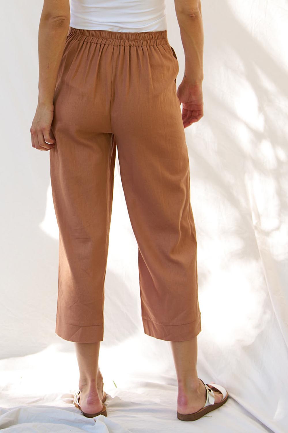 A model wearing the Parker Pant in colour Bronze, from the back