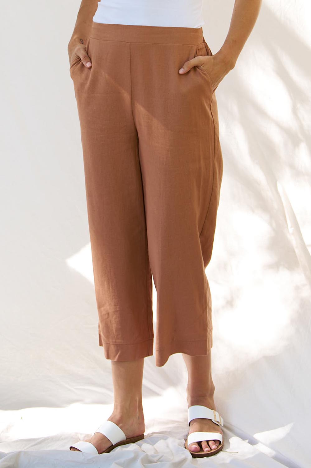 A model wearing the Parker Pant in colour Bronze, from the front, cropped image