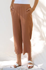 A model wearing the Parker Pant in colour Bronze, from the front, cropped image