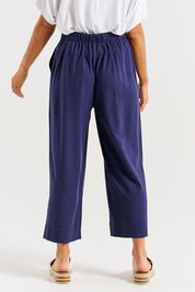 A model wearing the Parker Pant in colour Navy (Blue), from the back