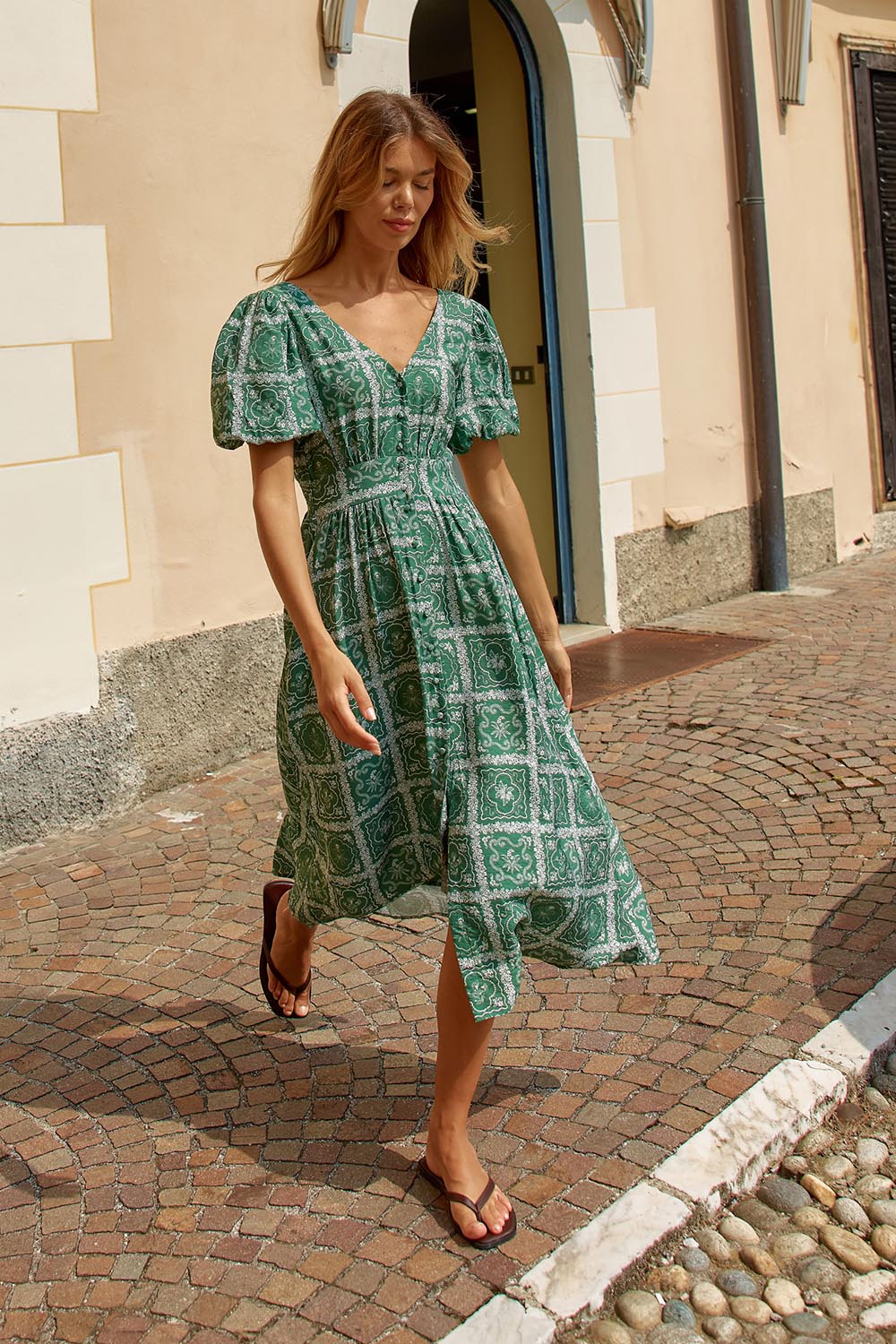A model wearing the Dahlia Dress in colour Floral (Green), from the front, showing the whole outfit