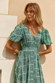 A model wearing the Dahlia Dress in colour Floral (Green), from the front, showing the whole outfit