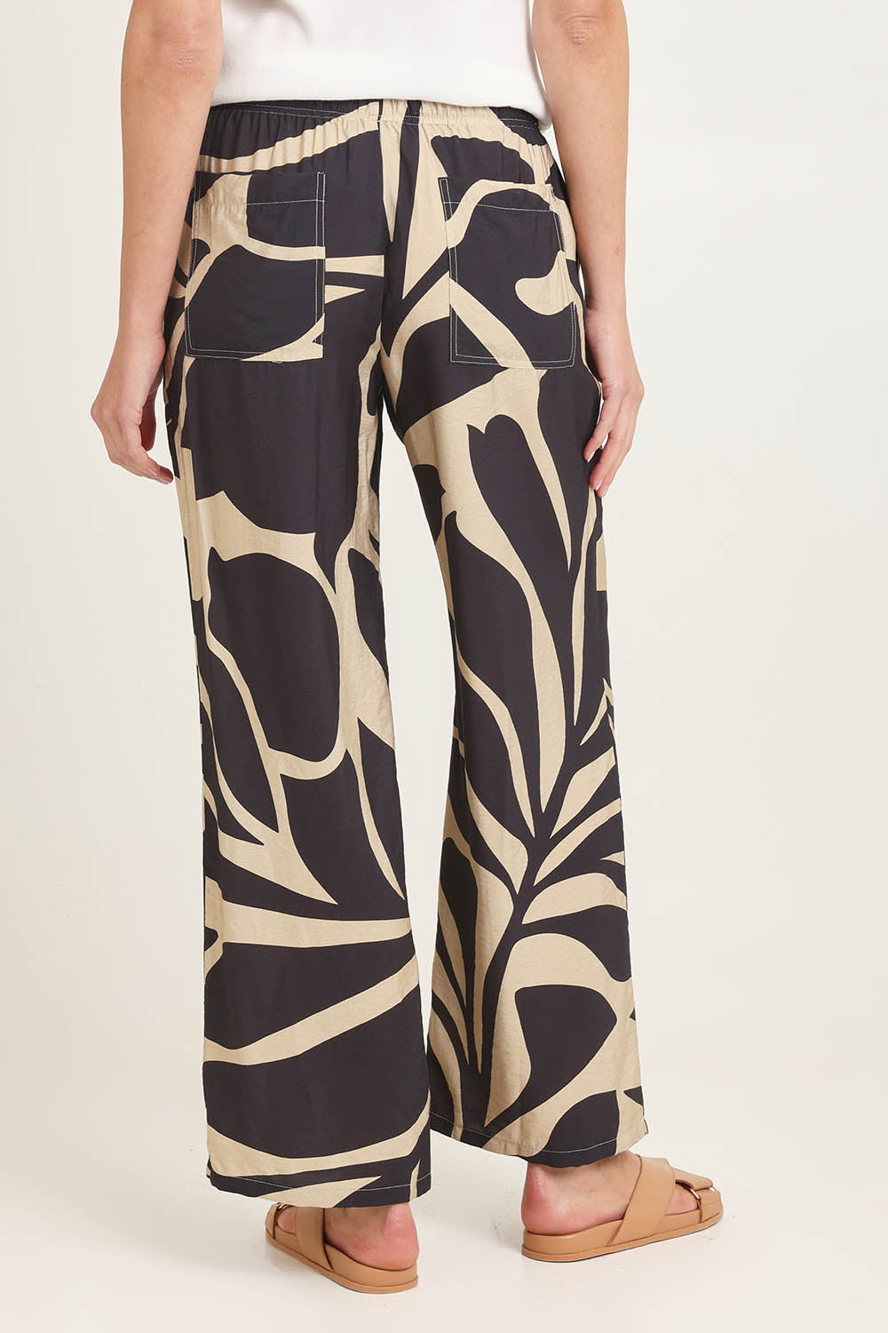 Model Madeline wearing size 10 of the Sutton Relax Pant in colour Floral (Black), from the back