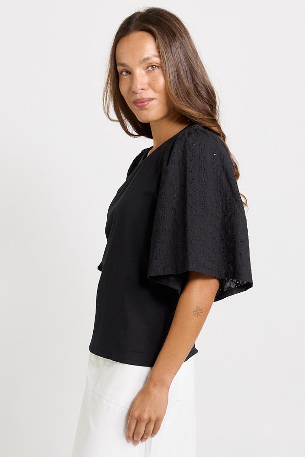 Model Genericm wearing size sample of the Bianca Broderie T-Shirt – Black in colour Black, from an angle