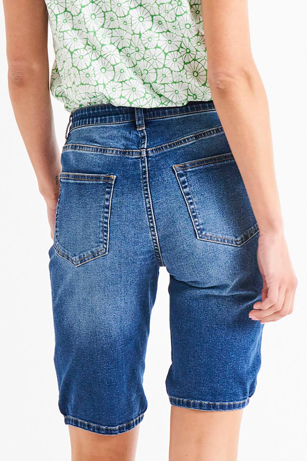 A model wearing the Bonnie Bermuda Denim Short in colour Indigo (Blue), from the back