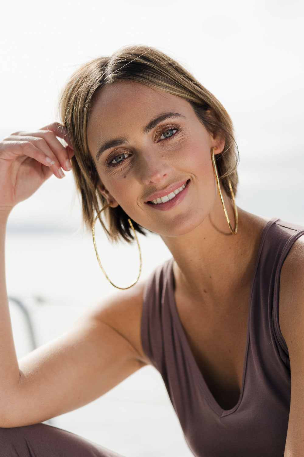 Model Tegan wearing size OneSize of the Brass Hammered Oversize Open Hoop Earrings in colour Goldbrass (Metallics), from the front, showing the whole outfit