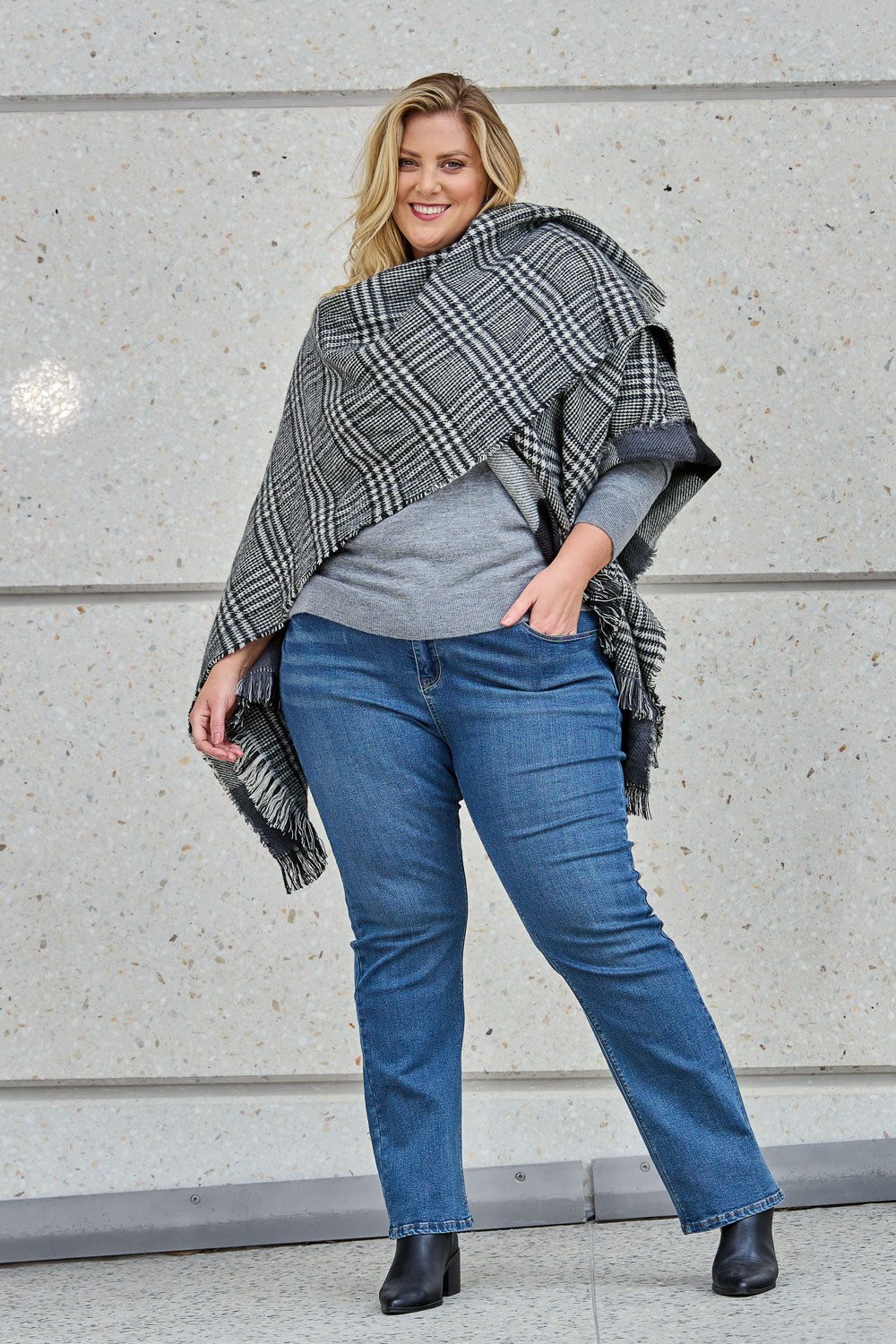 Model Caitlin wearing size OneSize of The Keepers Check Cape in colour Blackivory (Black), from the front, showing the whole outfit