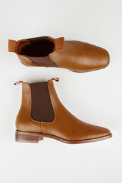 A model wearing size 37 of the Vegan Leather Pull On Flat Boot in colour Tan, from the front, showing the whole outfit