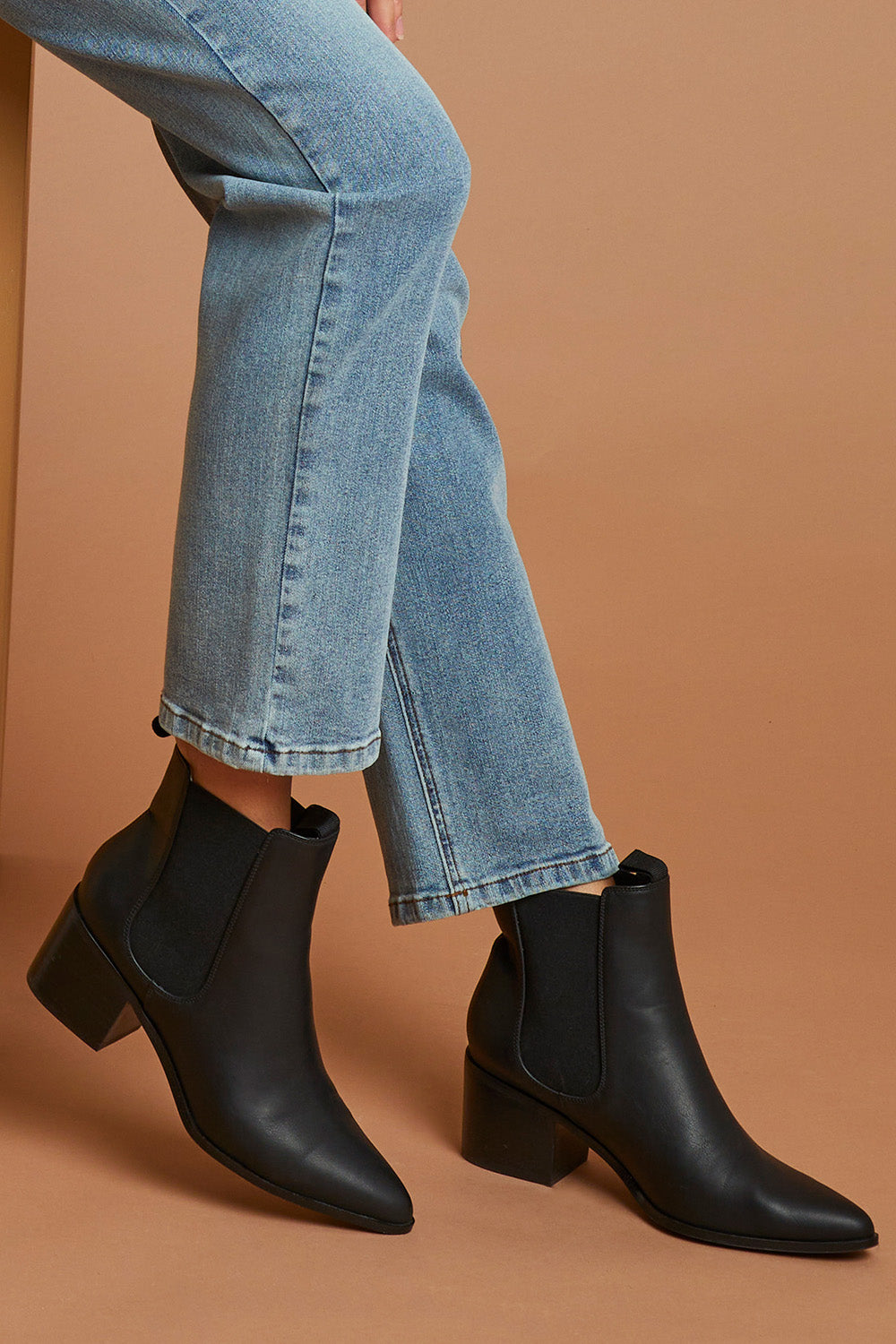 A model wearing size 37 of the Vegan Leather Pull On Heeled Boot in colour Black (Black), from the front, showing the whole outfit