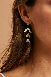 A model wearing size OneSize of the Leaf Long Drop Earrings in colour Gold (Metallics), from the front, showing the whole outfit