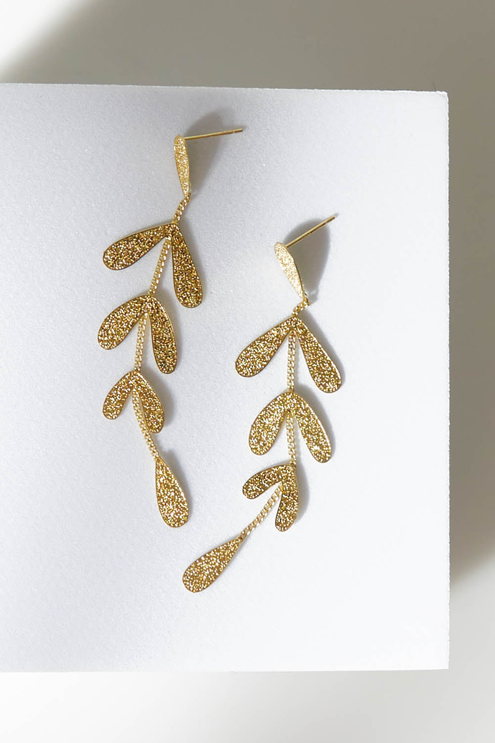 A model wearing size OneSize of the Leaf Long Drop Earrings in colour Gold (Metallics), from the front, showing the whole outfit