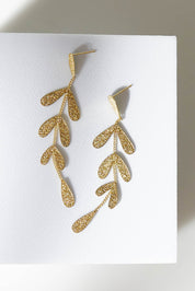 A model wearing size OneSize of the Leaf Long Drop Earrings in colour Gold (Metallics), from the front, showing the whole outfit