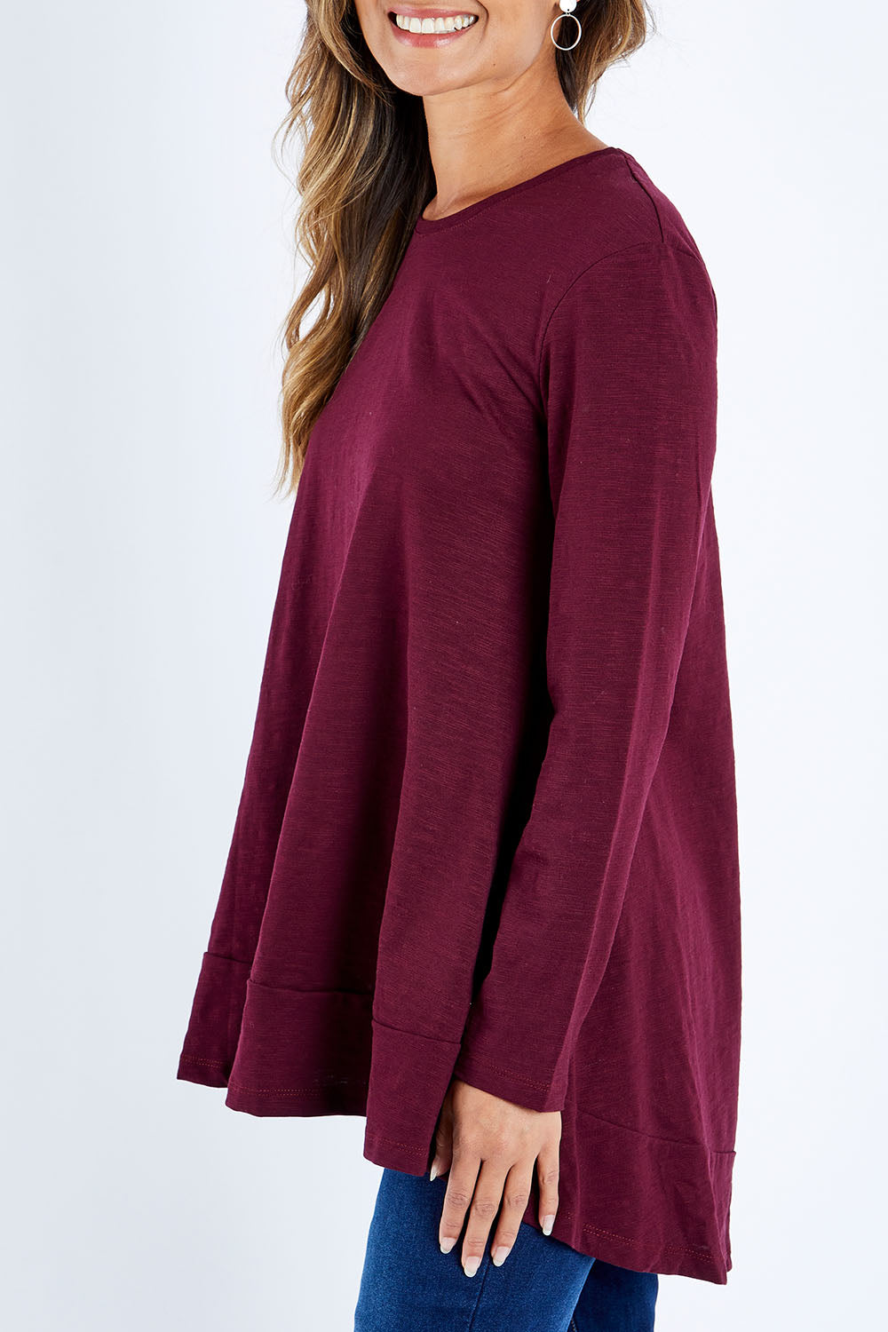 Model Kimberley wearing size 10 of The Long Sleeve Swing Tee in colour Shiraz (Red), from the front, cropped image