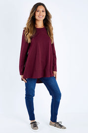 Model Kimberley wearing size 10 of The Long Sleeve Swing Tee in colour Shiraz (Red), from the front, showing the whole outfit