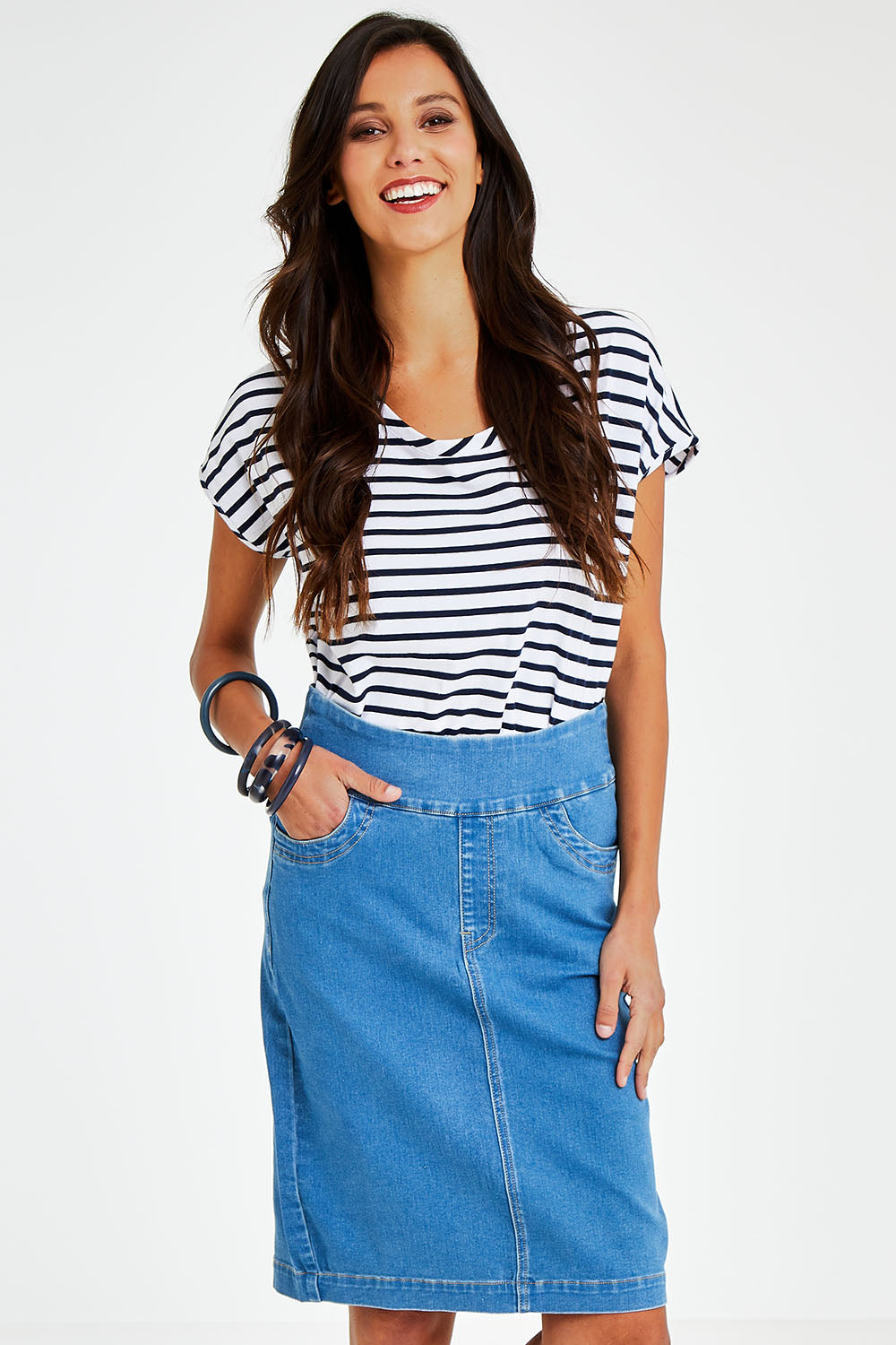 Model Vitoria wearing size 10 of The Pull On Denim Skirt in colour Middenim (Blue), from the front, cropped image