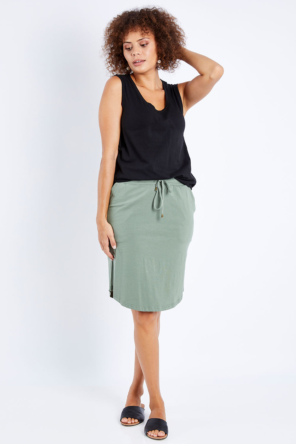 Model Lala wearing size 10 of The Drawcord Skirt in colour Khaki (Green), from the front, showing the whole outfit